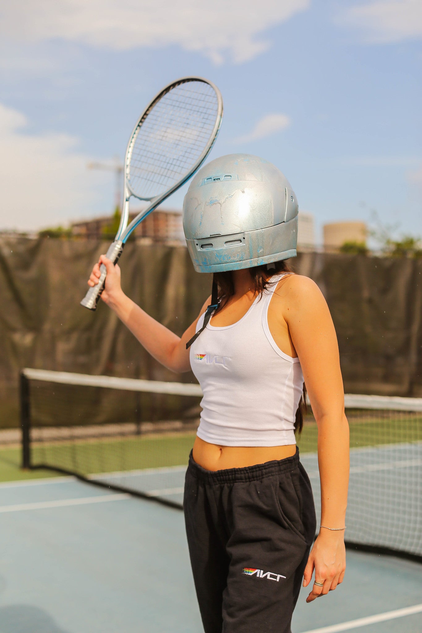 women in tank playing tennis with helmet