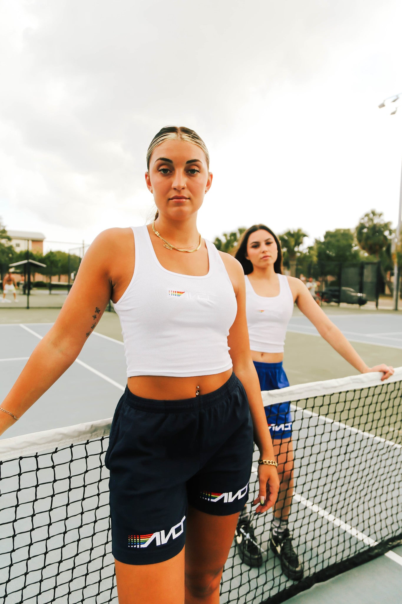 two women waering tanks on tennis court